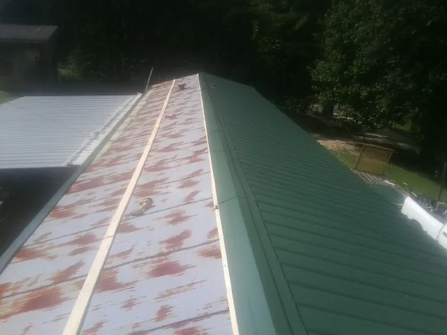 Old rusted panels beside newly installed green metal roofing — Wind Damage Roof Repair by Roofing Brothers in Fisherville