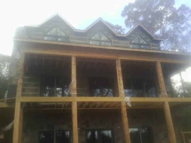 Dormers and porch framing on a large log home under construction — Roof Coating work by our crew in Fisherville