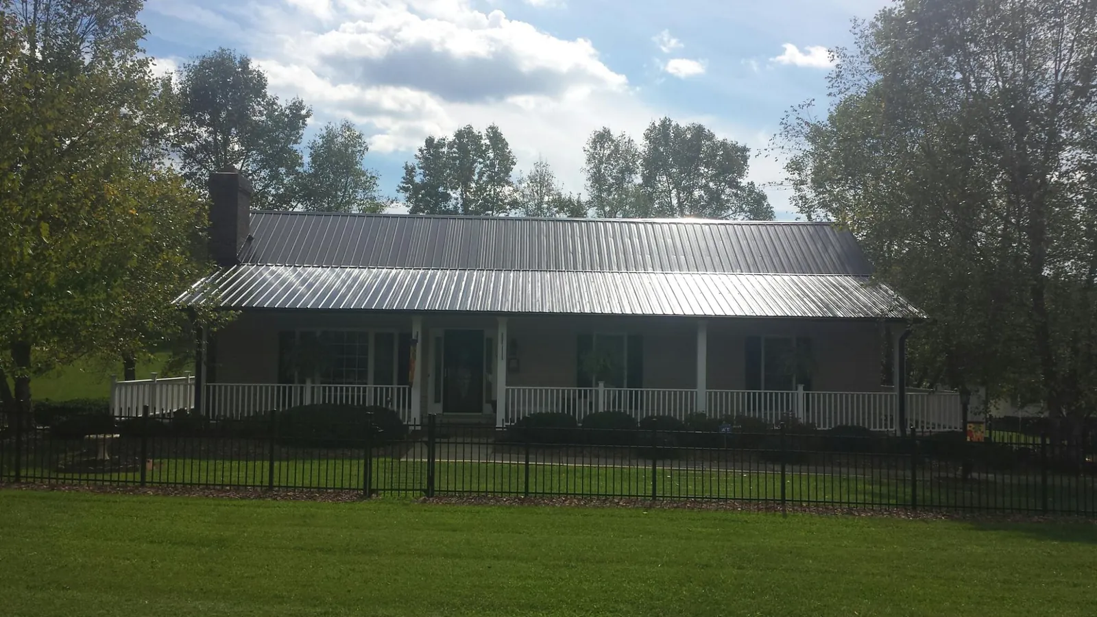 Gray metal roof on a brick ranch with a full width front porch — Gutter Guard Installation work by our crew in Fisherville
