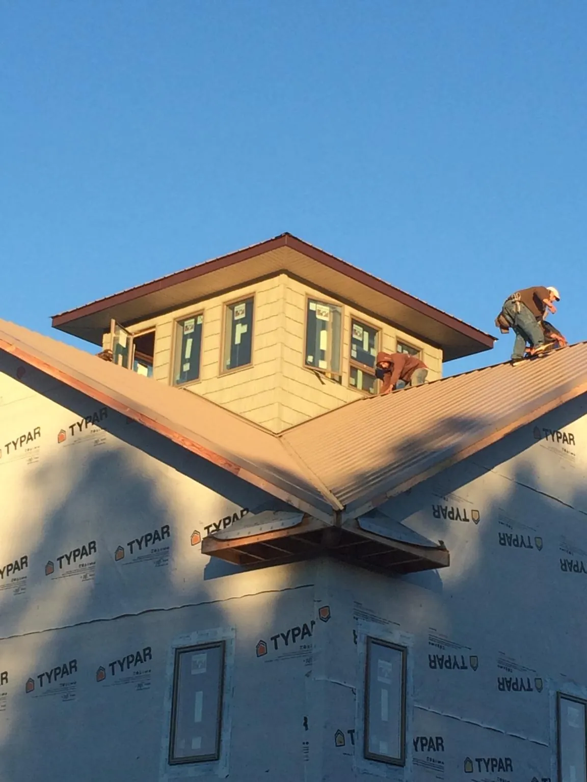 Roofers working around a rooftop cupola on a new metal roof at sunset — Roof Waterproofing in Fisherville by Roofing Brothers